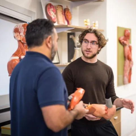 Health care science student talking to a faculty member in the classroom